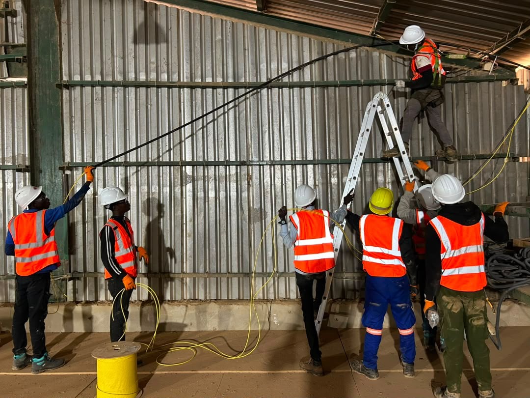 Équipe Bambara High Tech-Services en train de tirer des câbles dans un hangar